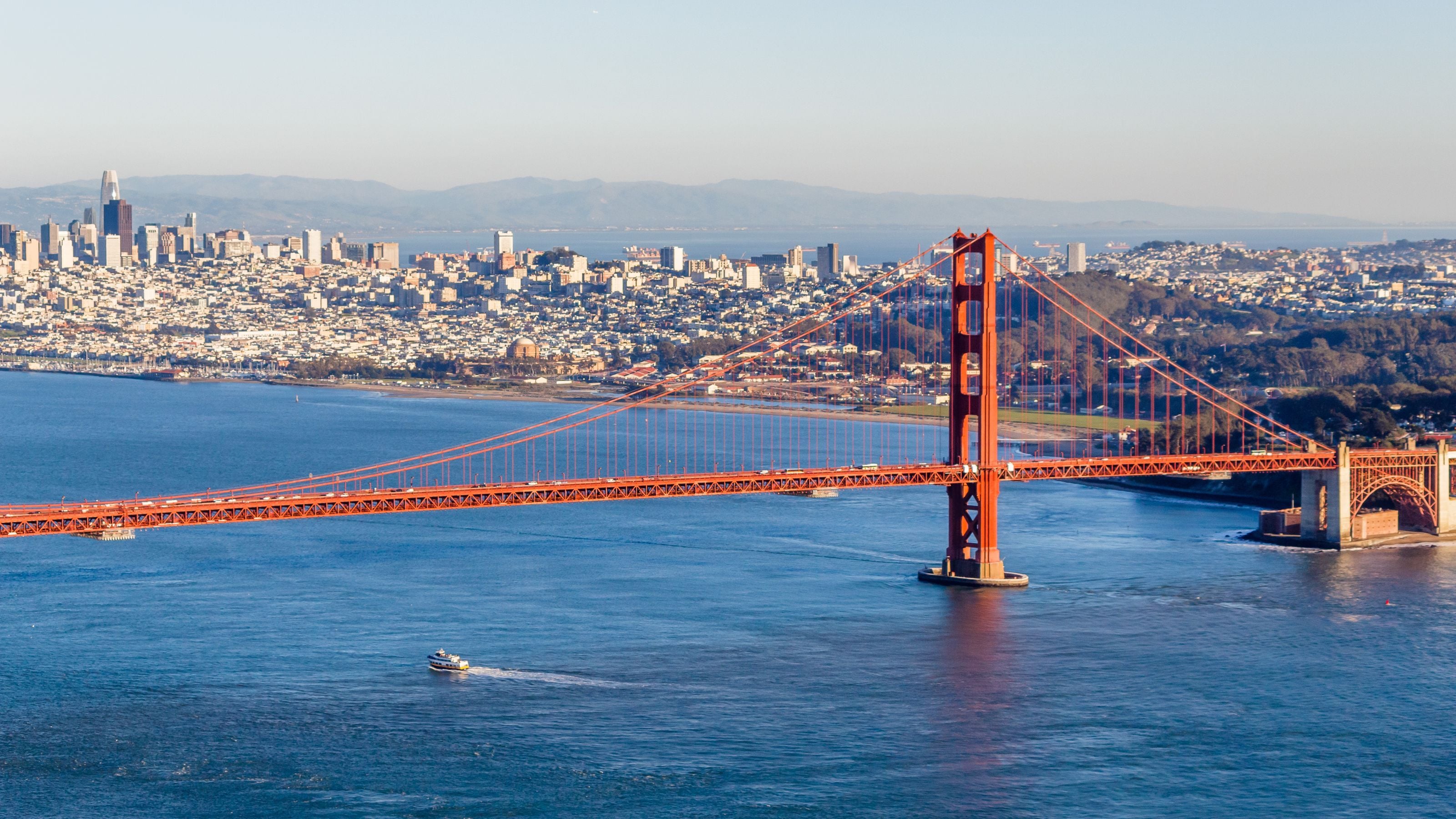 Aerial view of the iconic Golden Gate Bridge with San Francisco cityscape in the background.