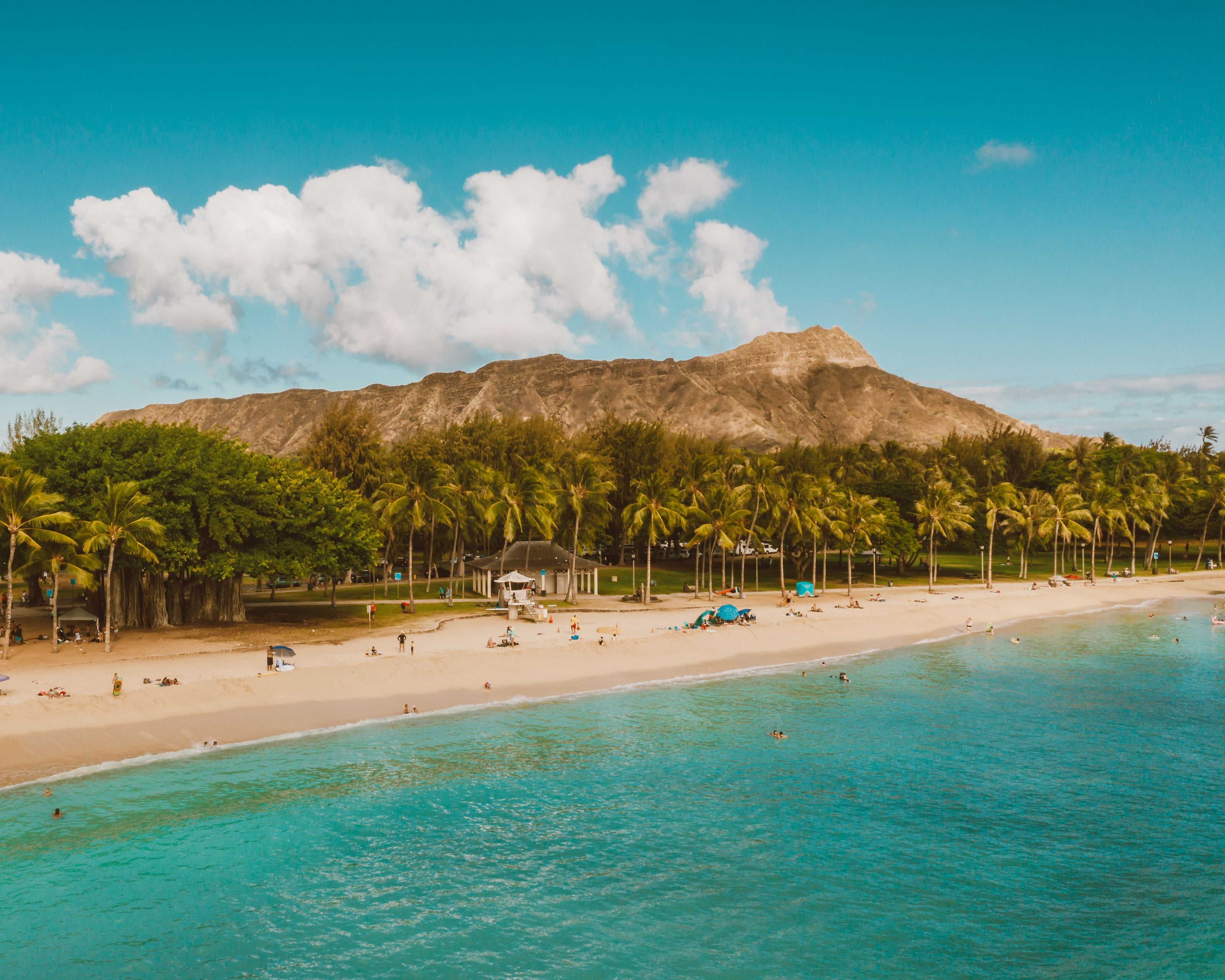 A scenic view of Waikiki Beach with Diamond Head in the background under a clear blue sky.