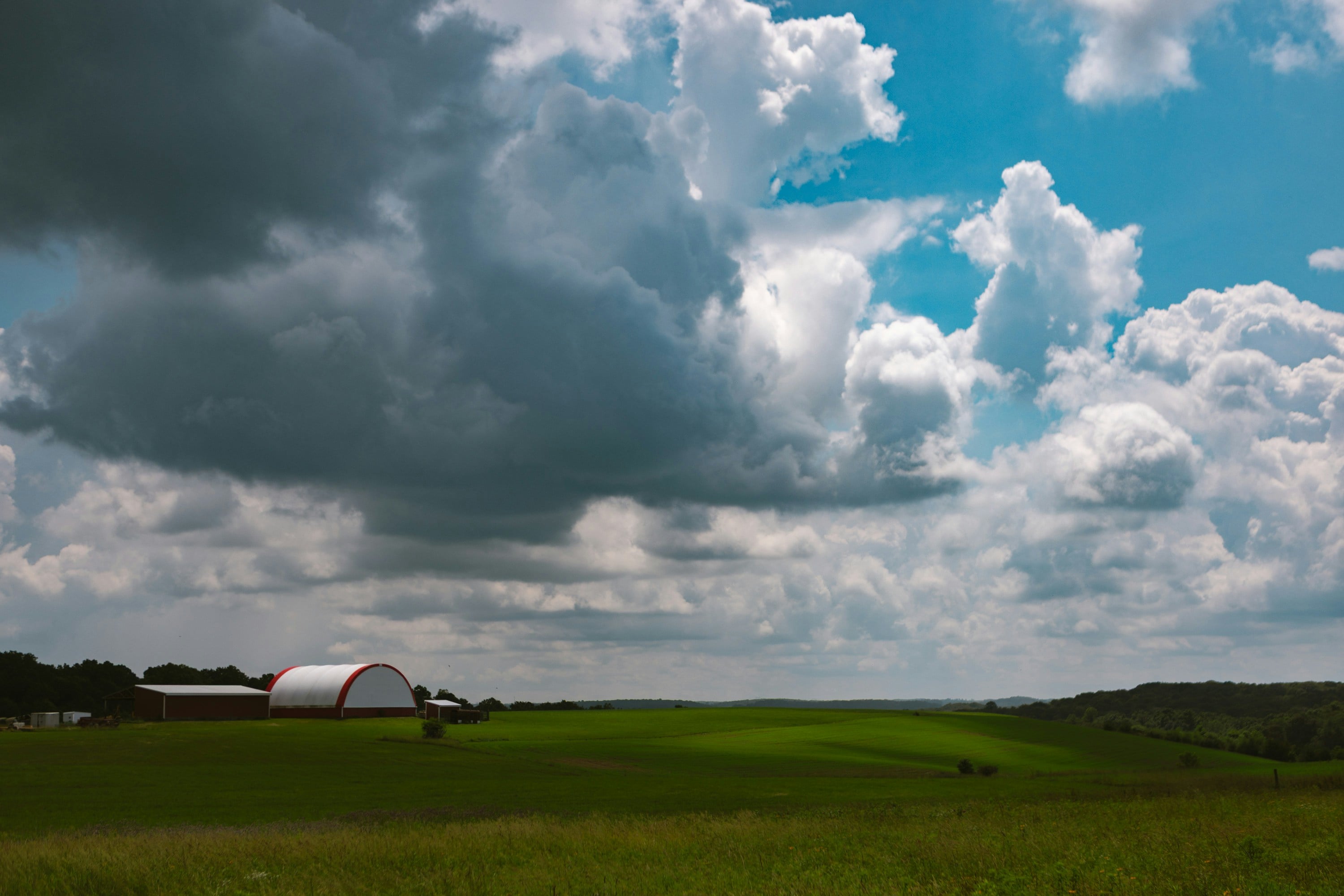 Green fields, fluffy clouds, and a distant farm.