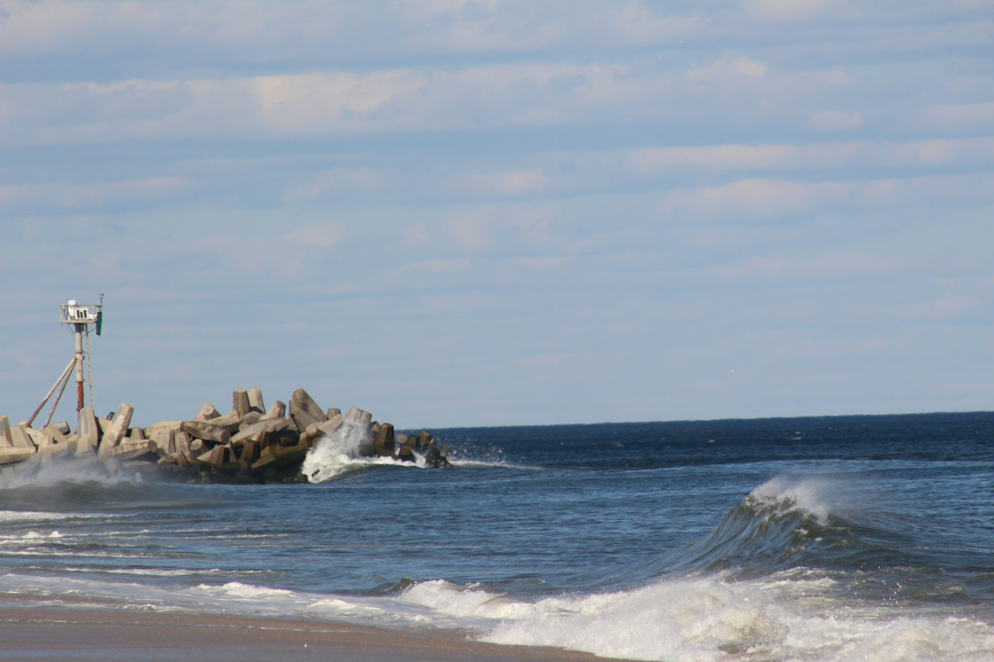 brown rocks on sea under white clouds during daytime